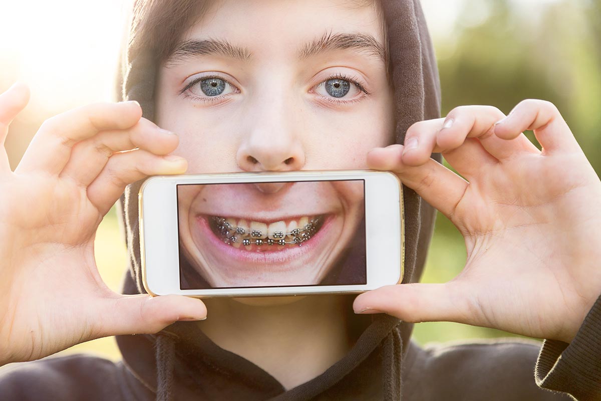 phone holding boy face dental teenage patients apps smile parents braces toledo oh
